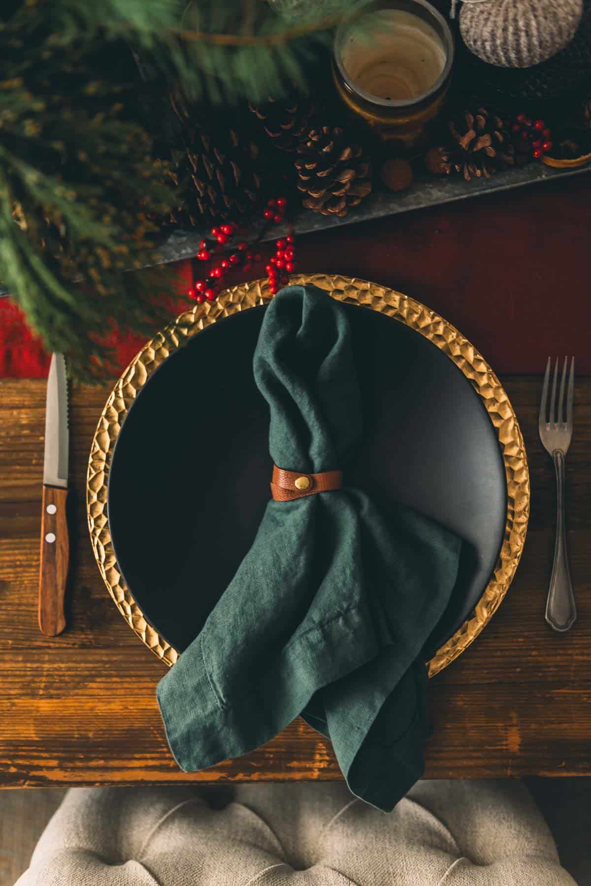 A plate with a napkin and fork on a wooden table.
