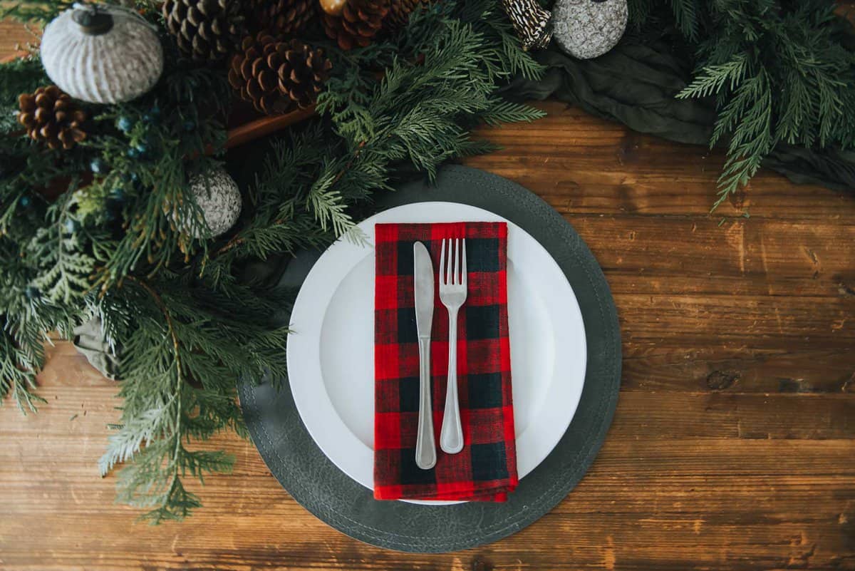 A christmas table setting with a plaid napkin and fork.