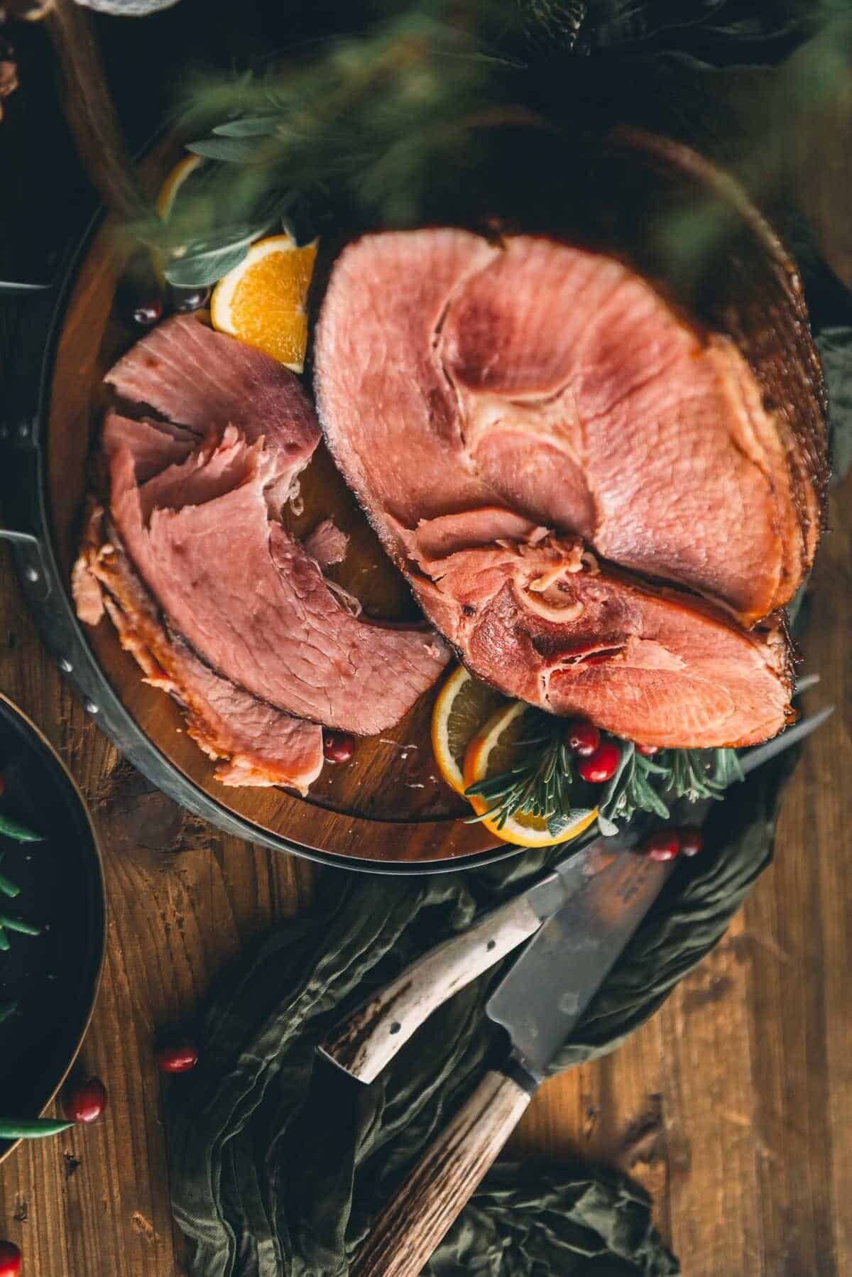 Sliced spiral ham on a wooden table with cranberries.