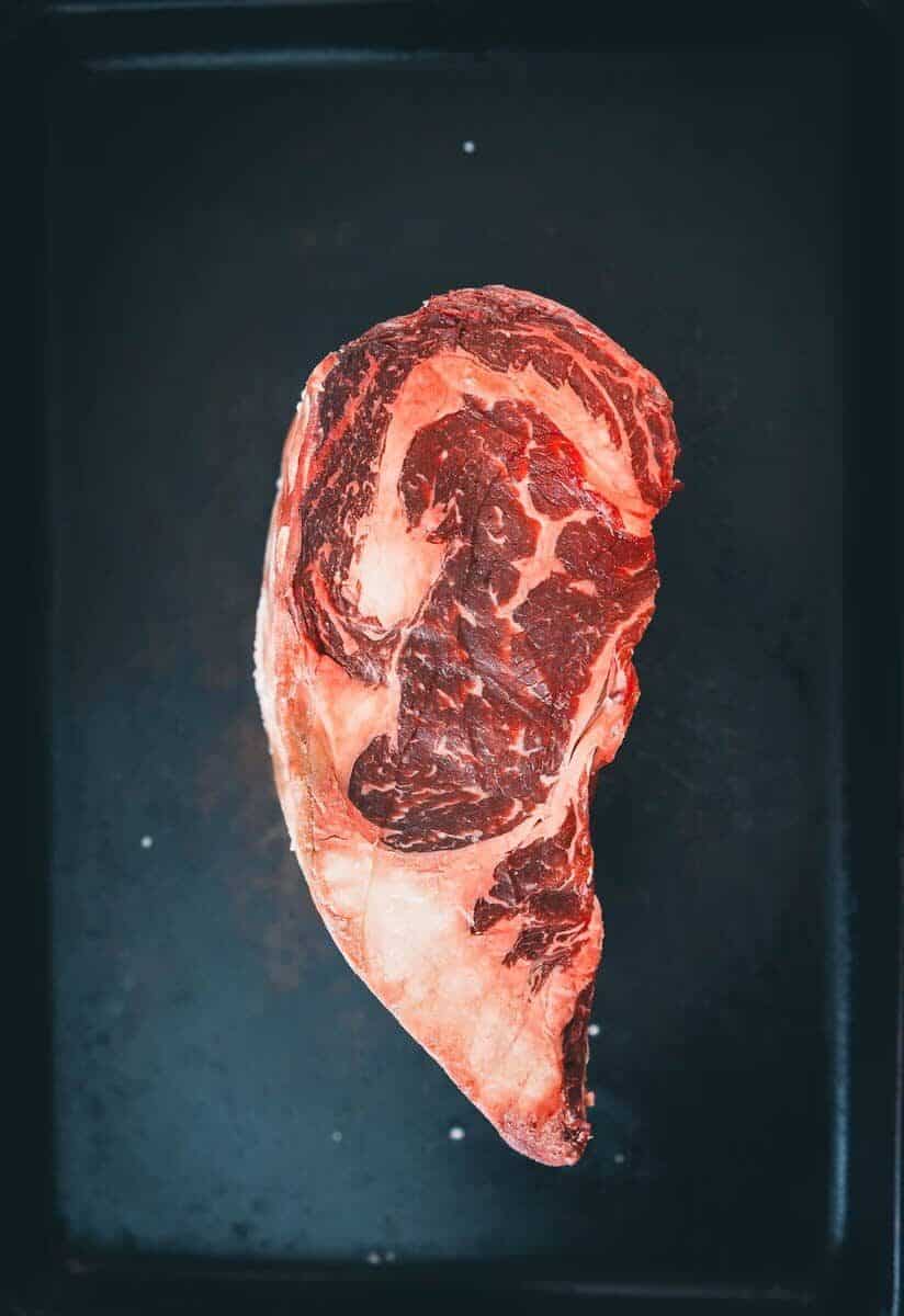 A piece of steak on a black tray.