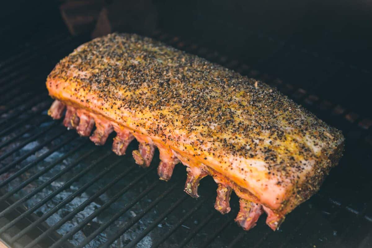 A piece of pork is being smoked on a grill.