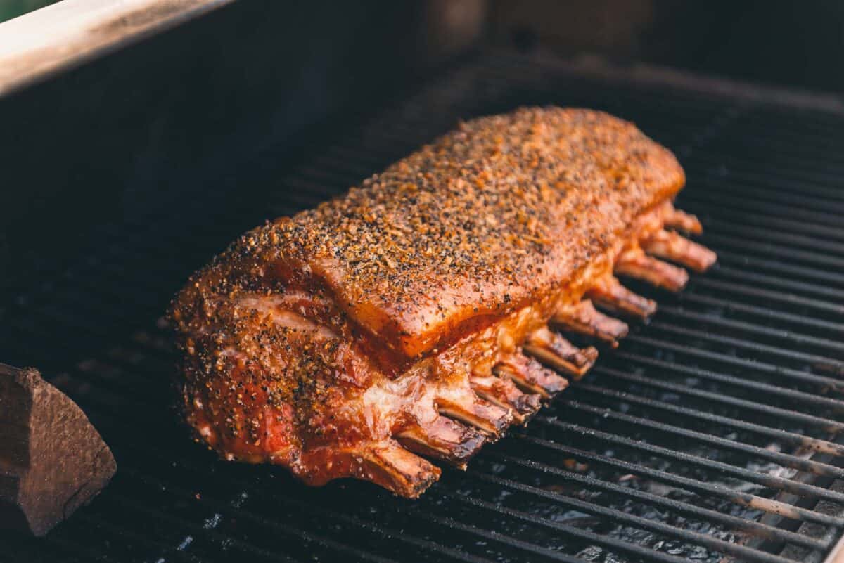 A rack of pork smoking on the grill grates.