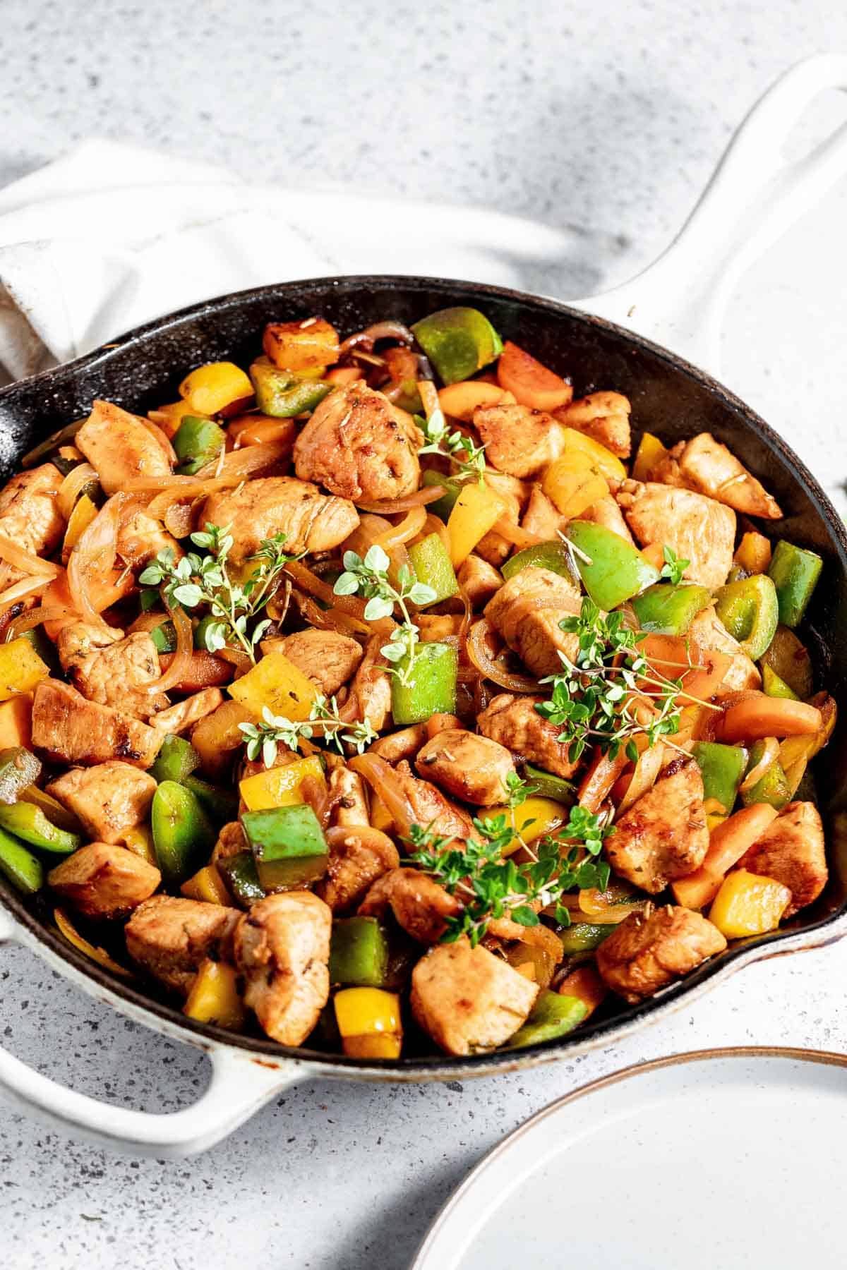 A skillet with chicken and vegetables in it.