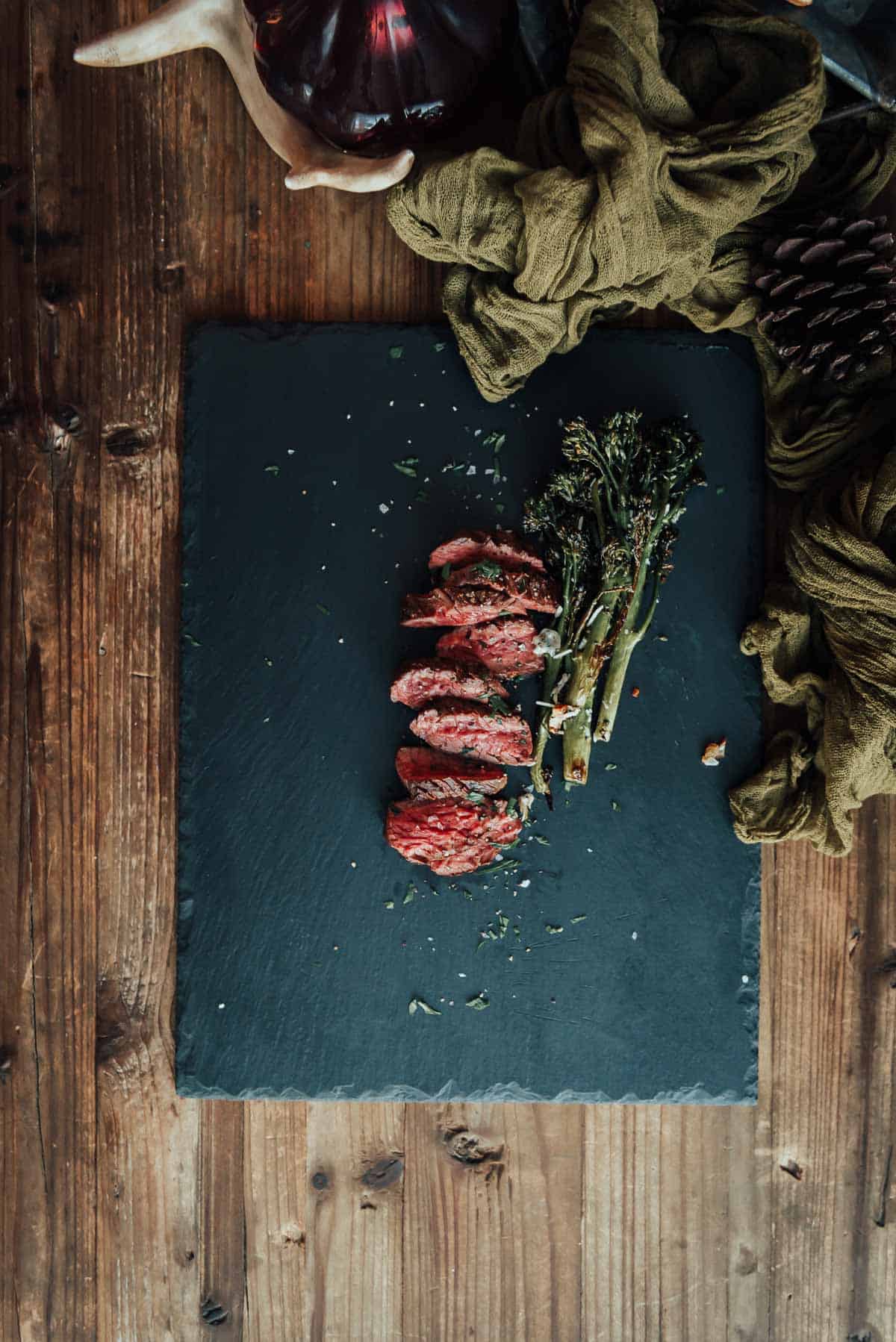 A sliced hanger steak on a slate plate on a wooden table.