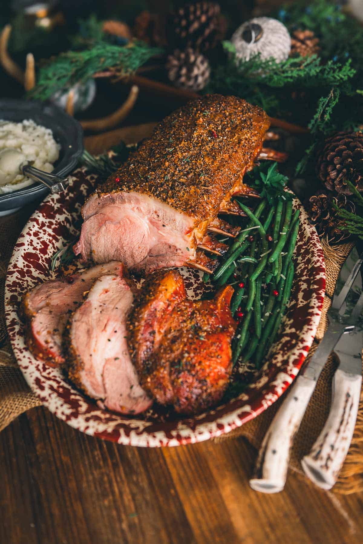 A plate of smoked pork with mashed potatoes and green beans on a wooden table.