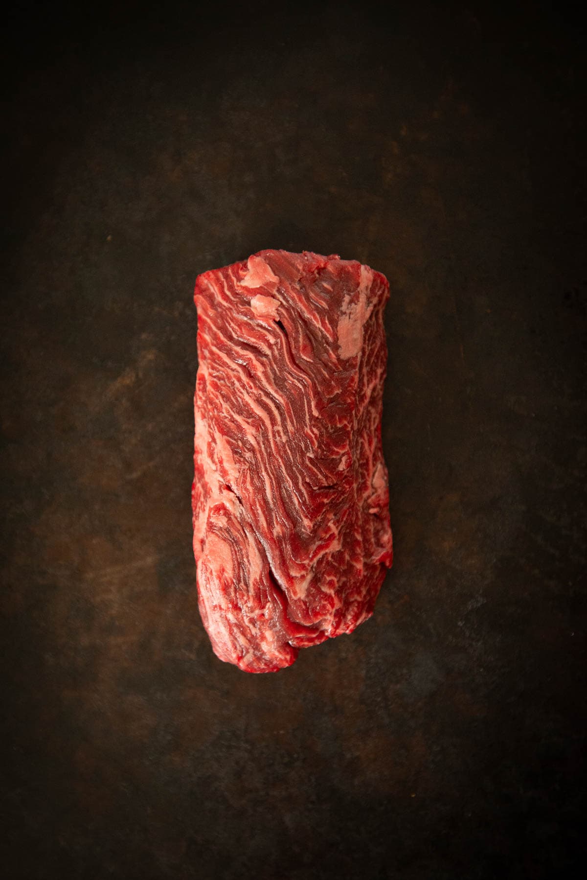 A piece of steak on a dark background.