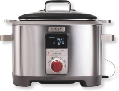 A stainless steel slow cooker with a red knob.