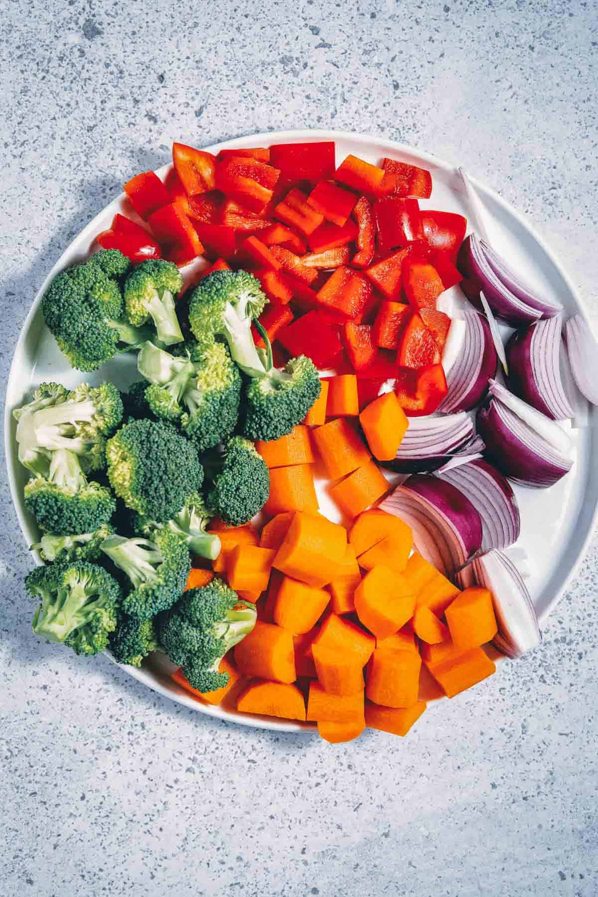 A plate of vegetables with broccoli, carrots and onions.