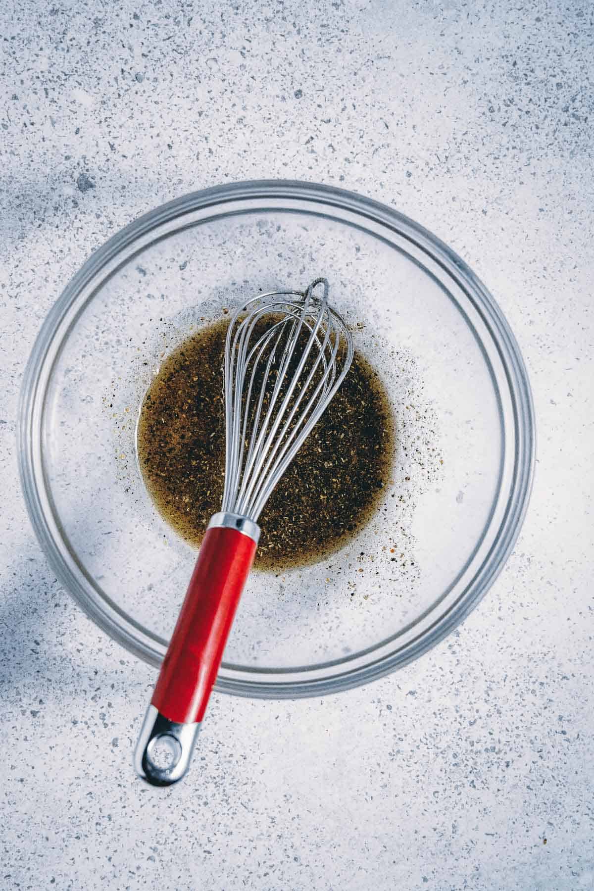 A whisk in a bowl with a sauce on it.