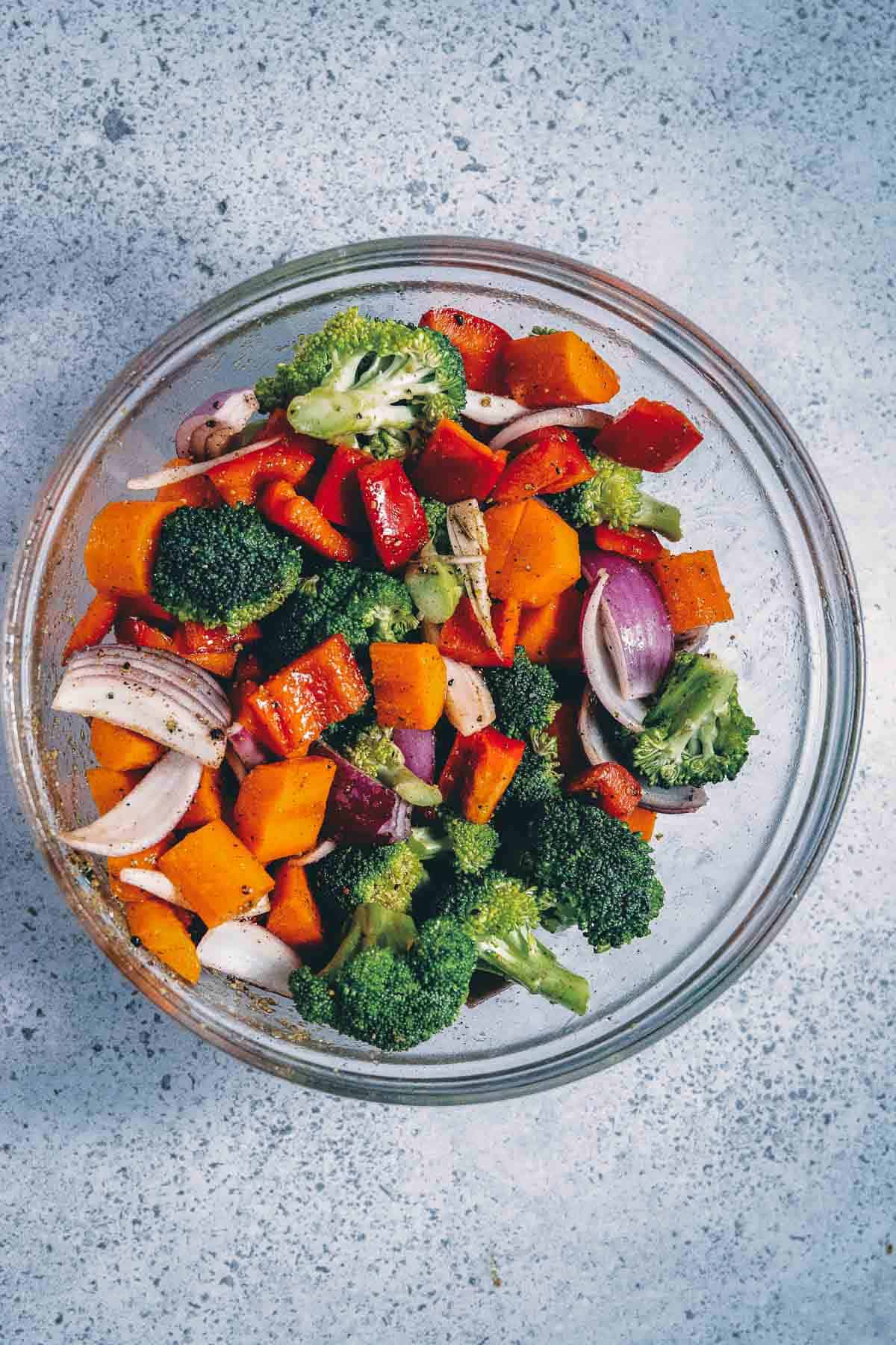 A bowl of vegetables with broccoli, carrots and onions.