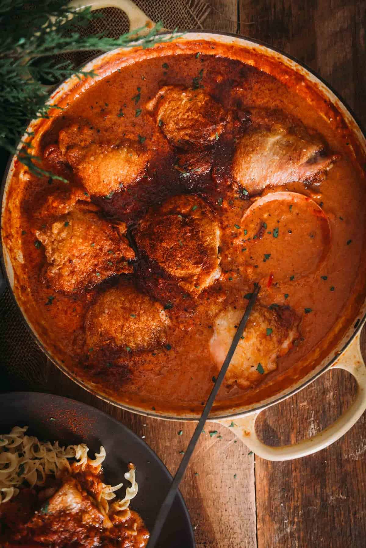 Chicken paprikash in a pan on a wooden table.