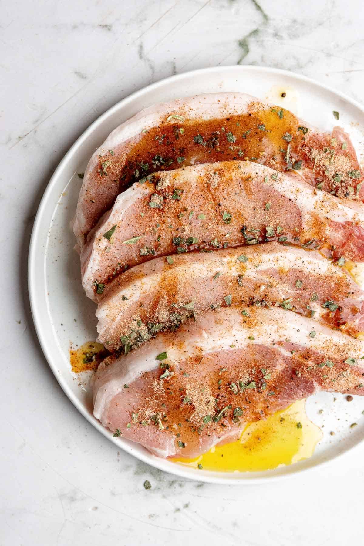 Pork chops with spices on a white plate.