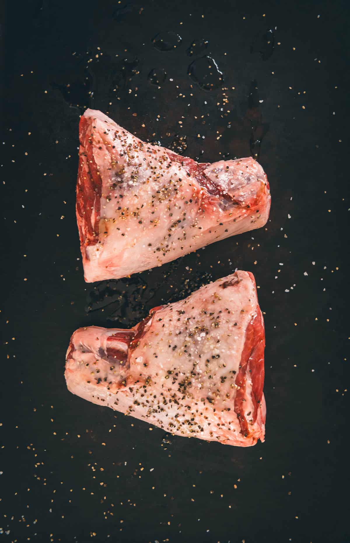 Two pieces of lamb on a black background.
