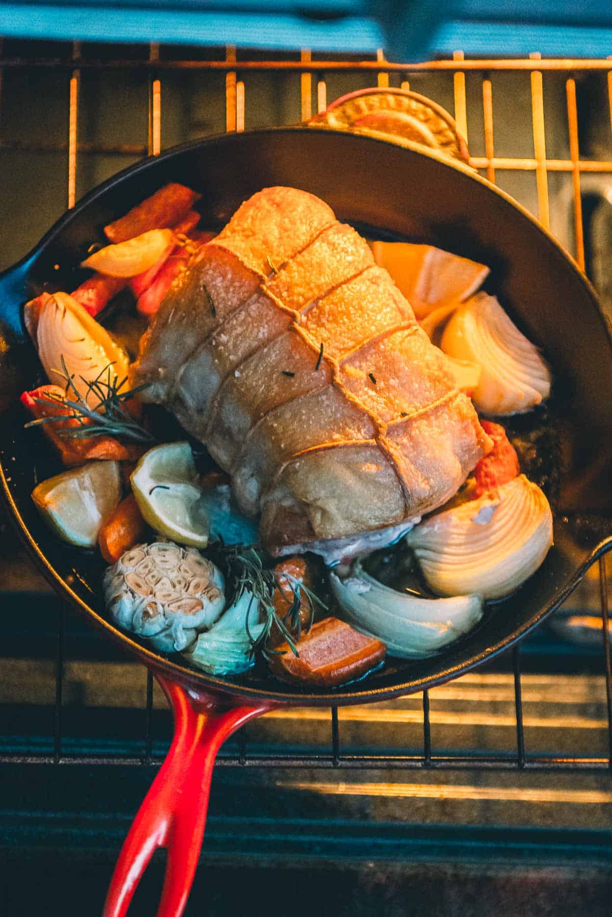 A skillet with a pork roast and vegetables going into the oven.