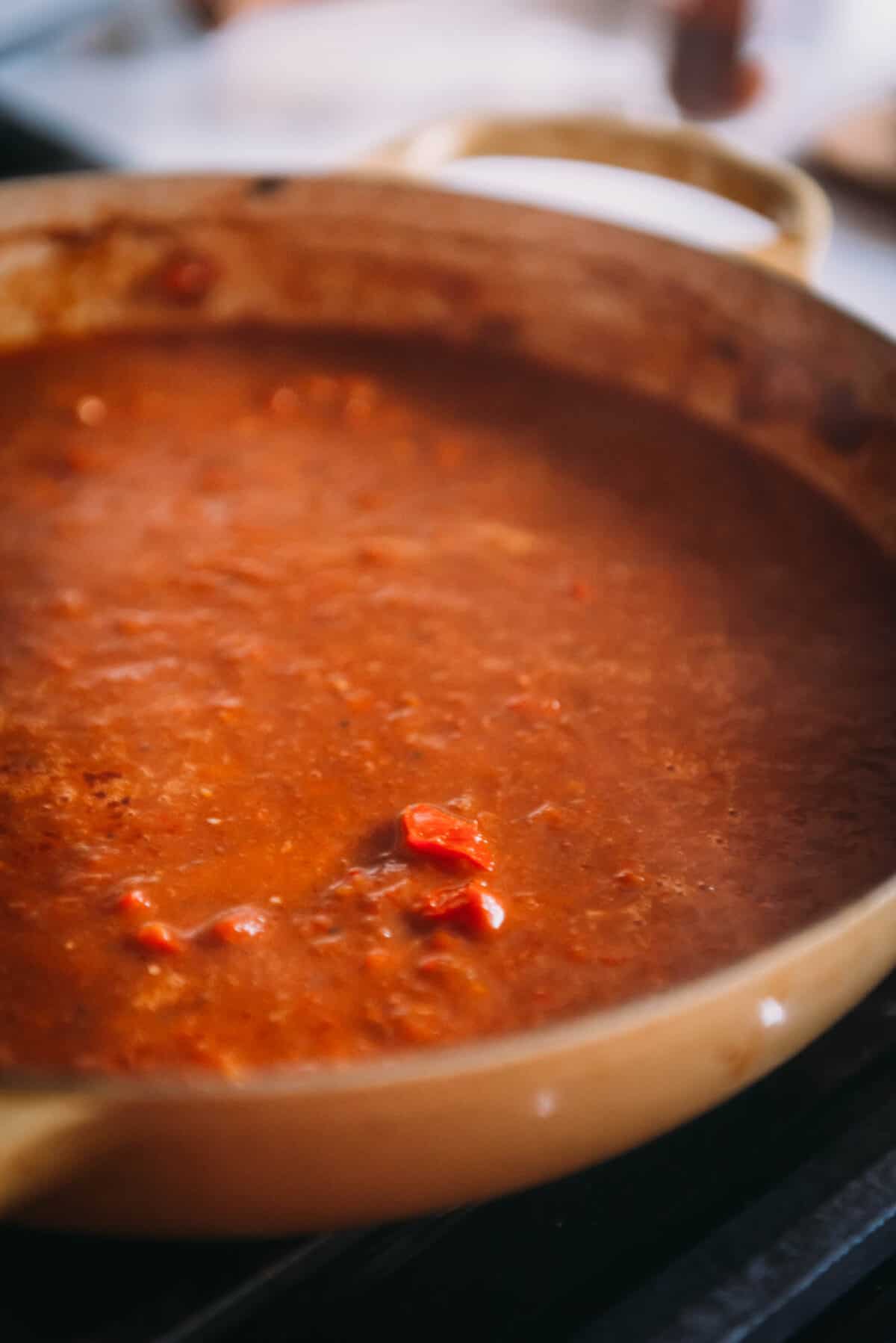A pot of red pepper sauce on top of a stove.