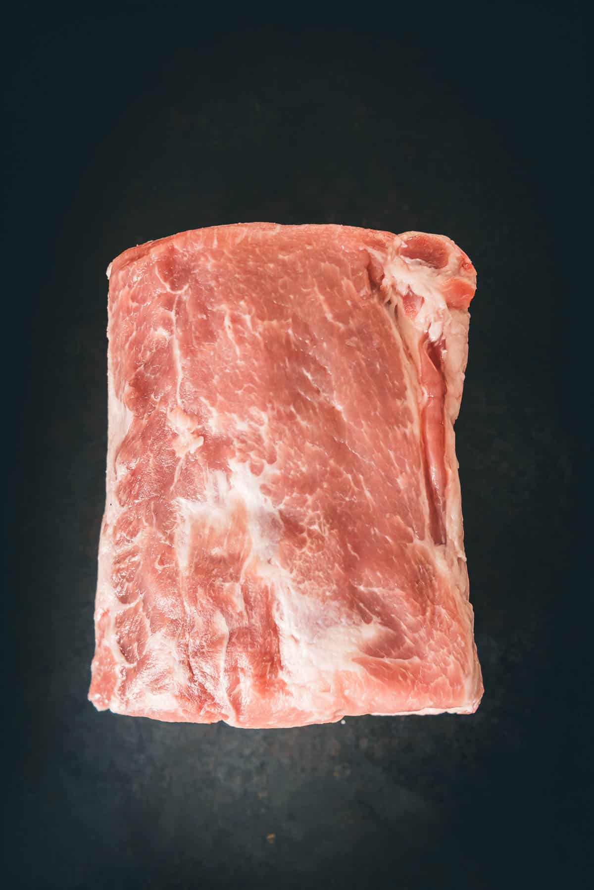 A pork loin roast on a black background.