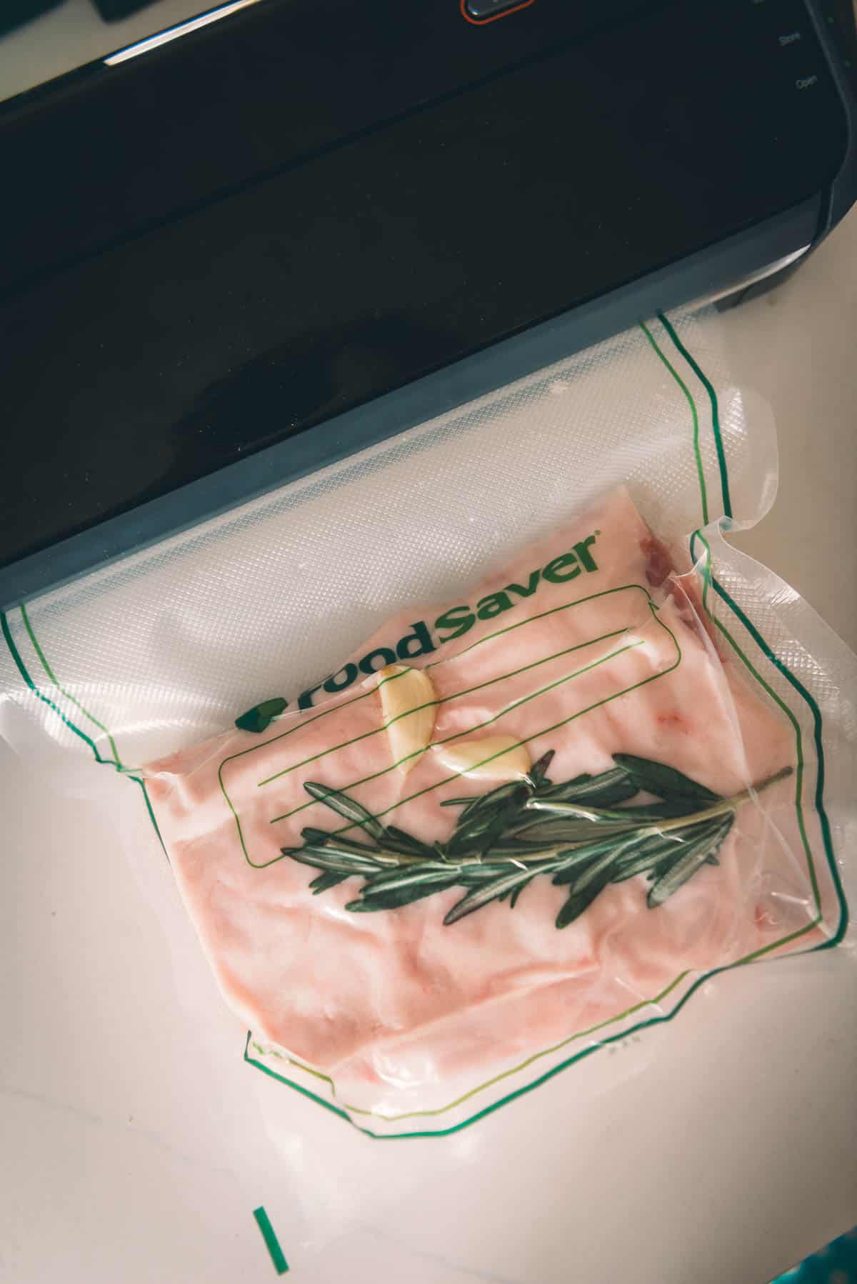 Pork loin in vacuum sealed bag with rosemary and garlic.