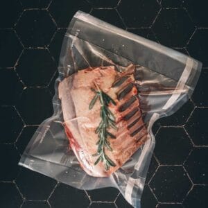 A rack of lamb in a vacuum bag with sprigs of rosemary.