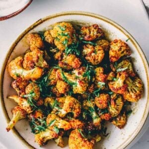 Roasted cauliflower in a bowl with sour cream.