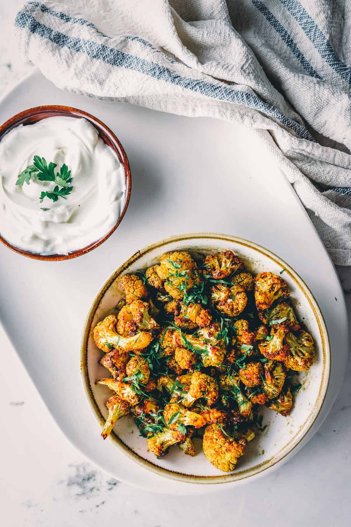 Cauliflower florets in a bowl with yogurt and sour cream.