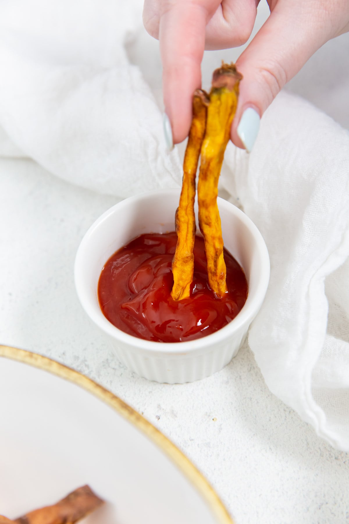 A person dipping french fries in ketchup.