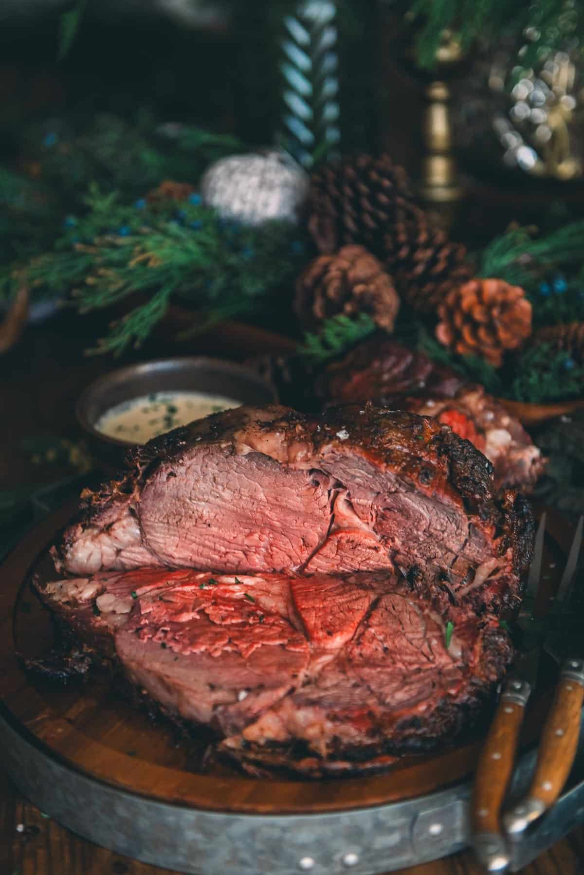 A prime rib thats been grilled and sliced on a wooden serving platter.