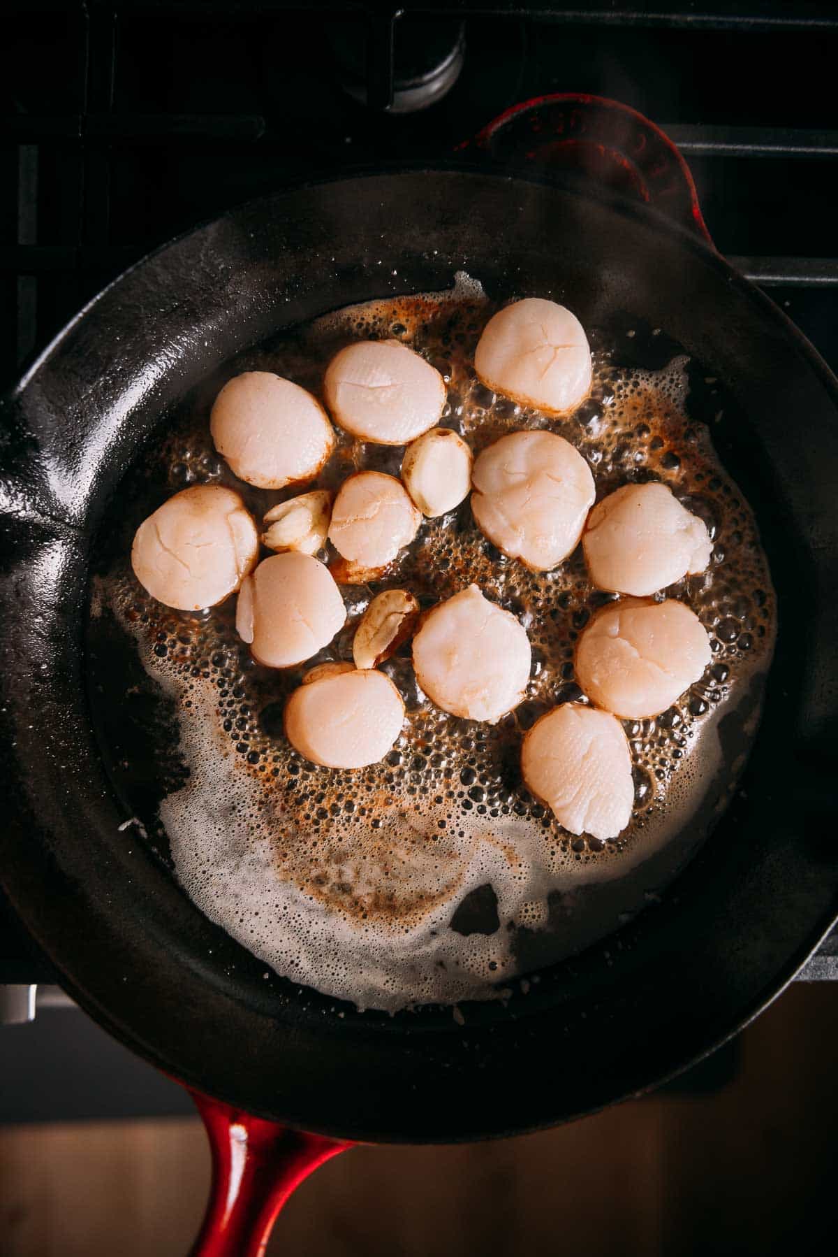 Sous vide scallops being seared in a large skillet.