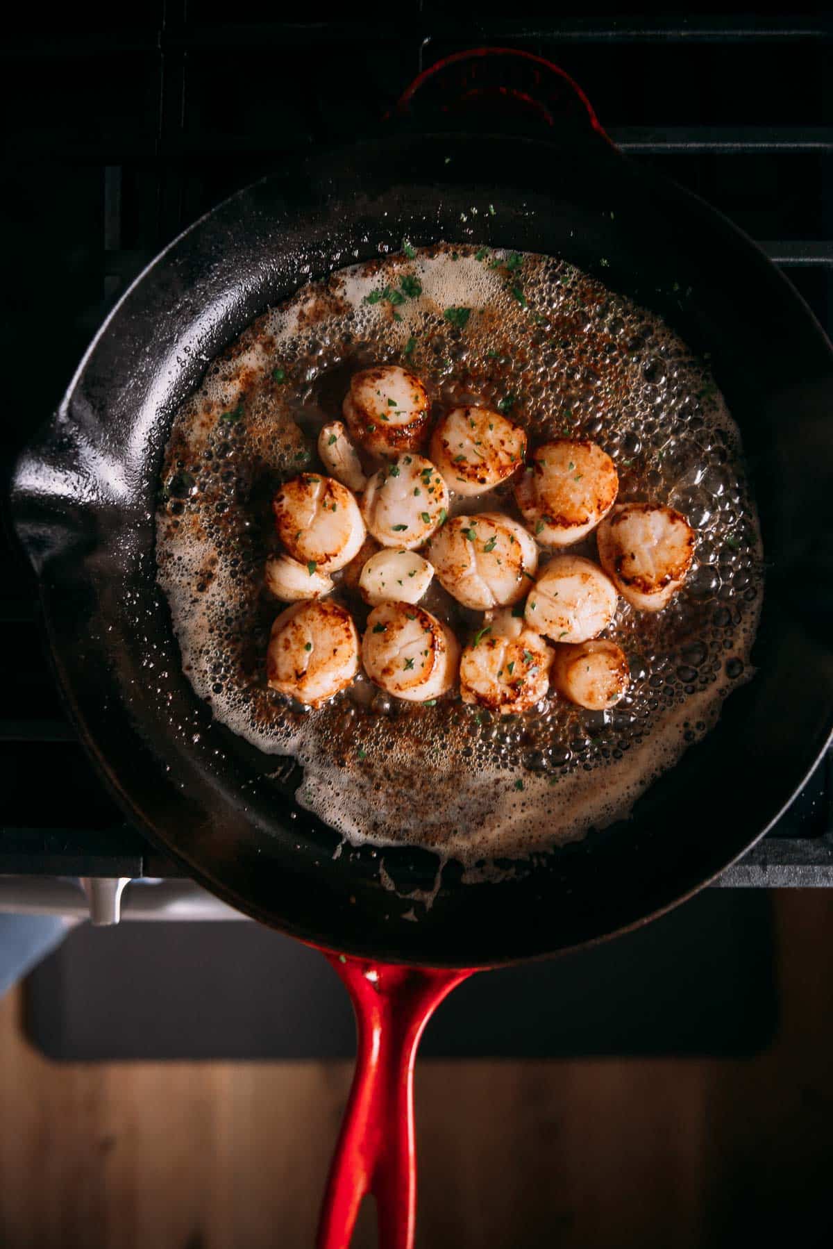 Scallops being seared in a skillet on the stove.