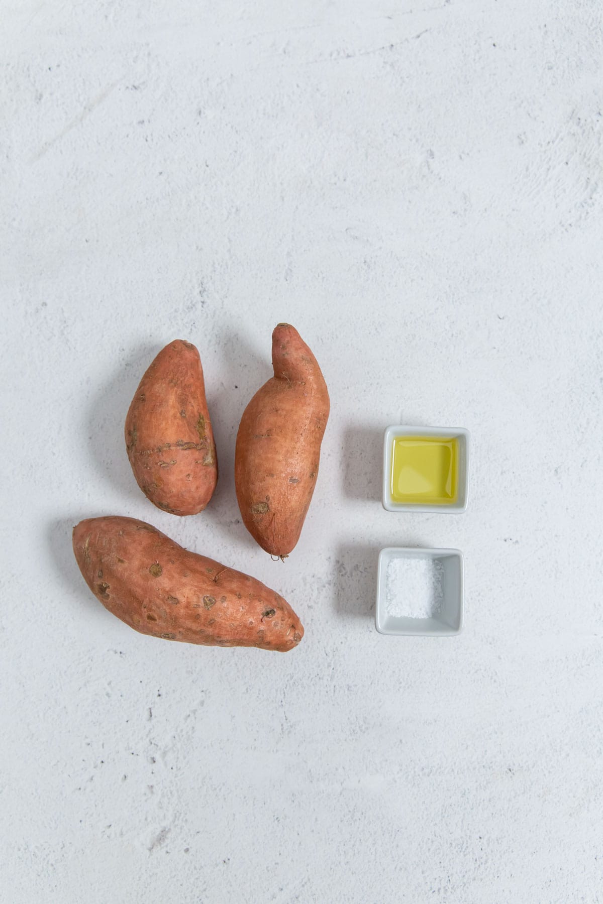 Sweet potatoes and oil on a white background.