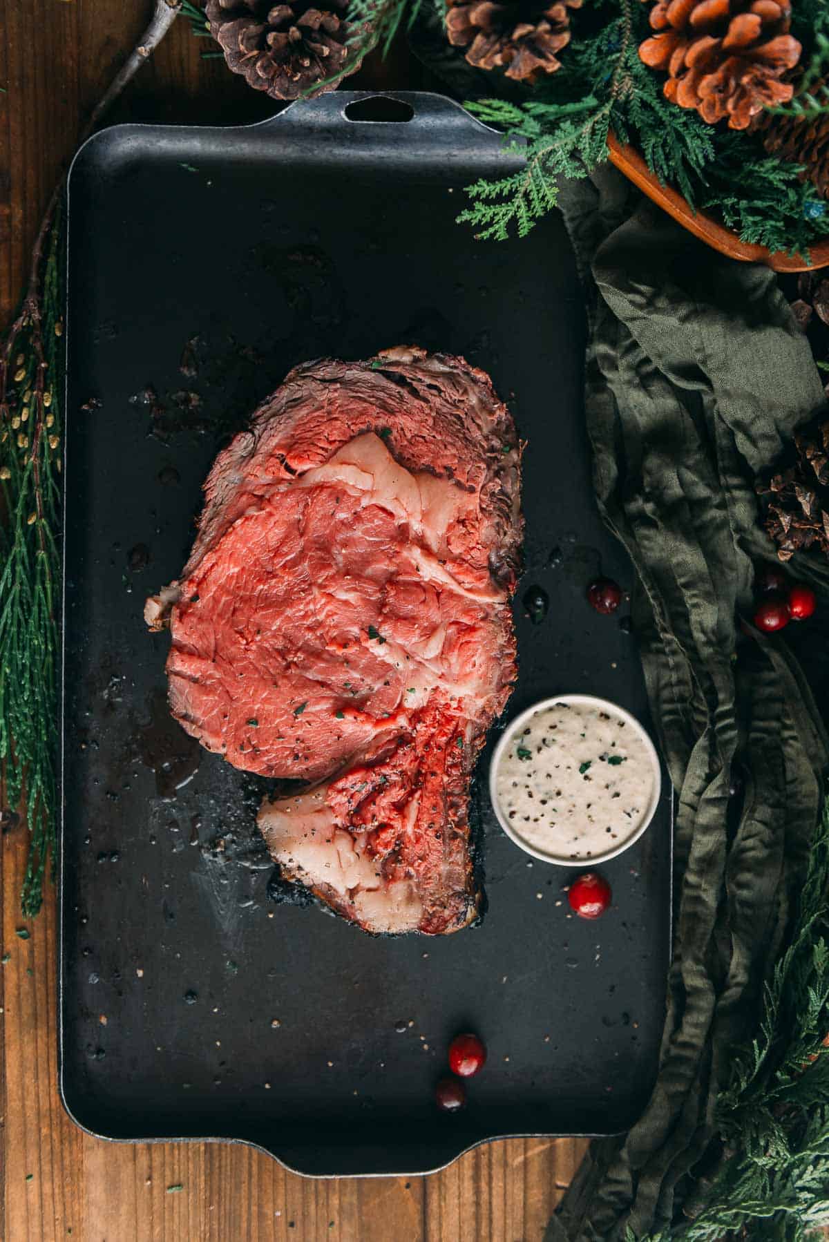 A piece of meat on a black surface next to a white sauce.