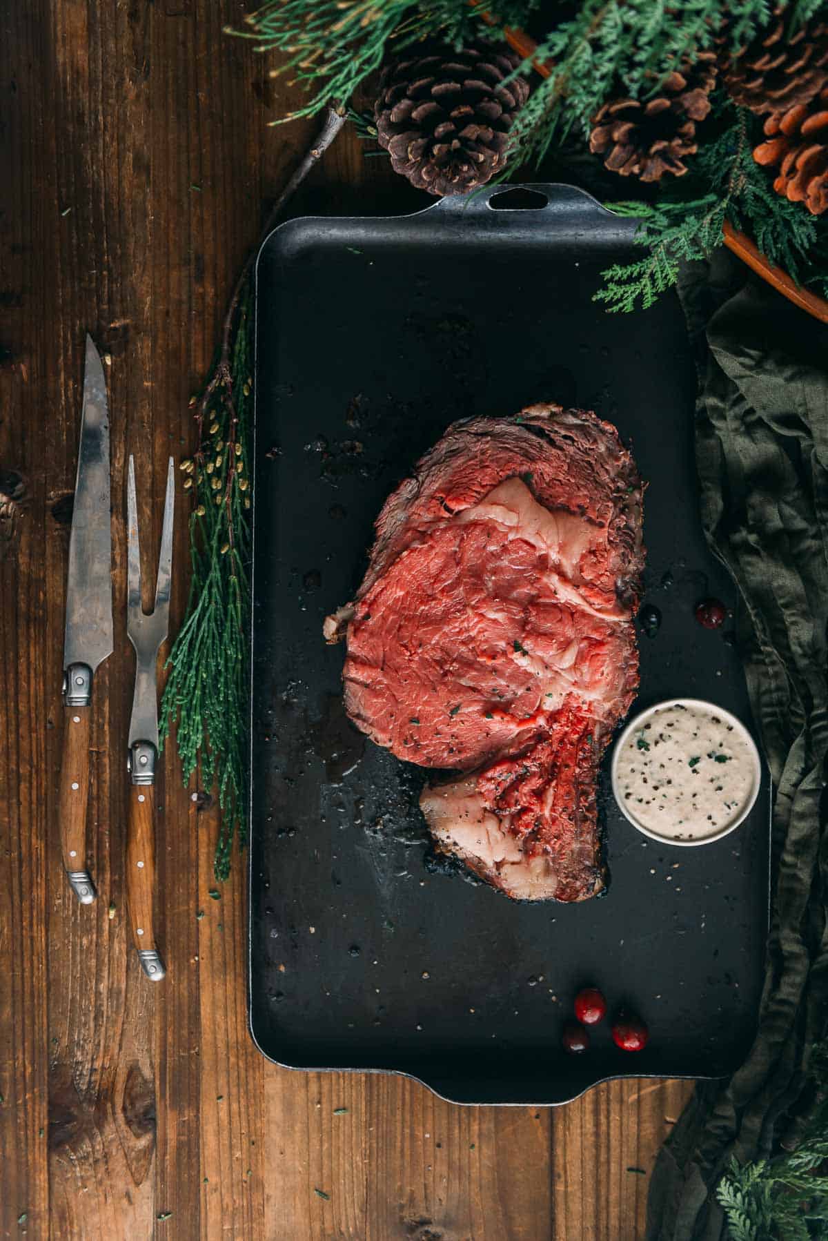 A piece of meat on a black plate next to a white sauce.