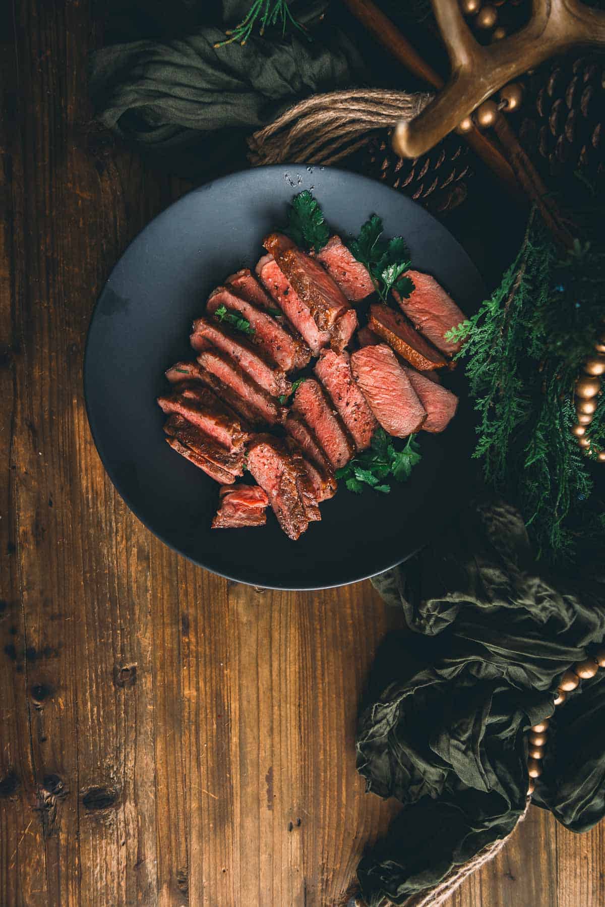 A plate of strip steak on a wooden table.