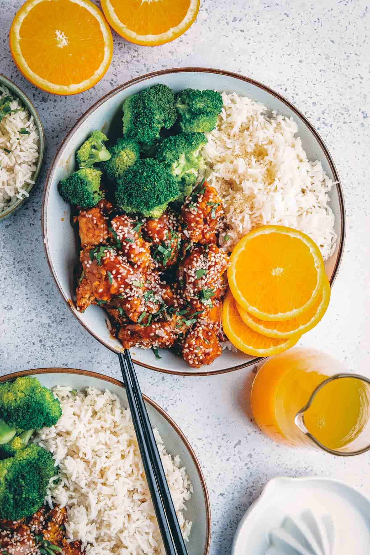 Air fryer orange chicken in a bowl with rice and steamed broccoli.