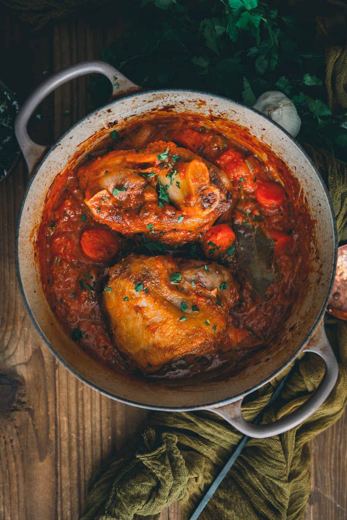 Chicken in tomato sauce in a pan on a wooden table.