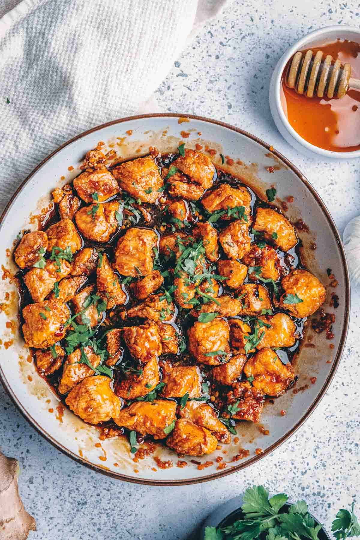 A plate of honey garlic chicken in a sauce with herbs and honey.