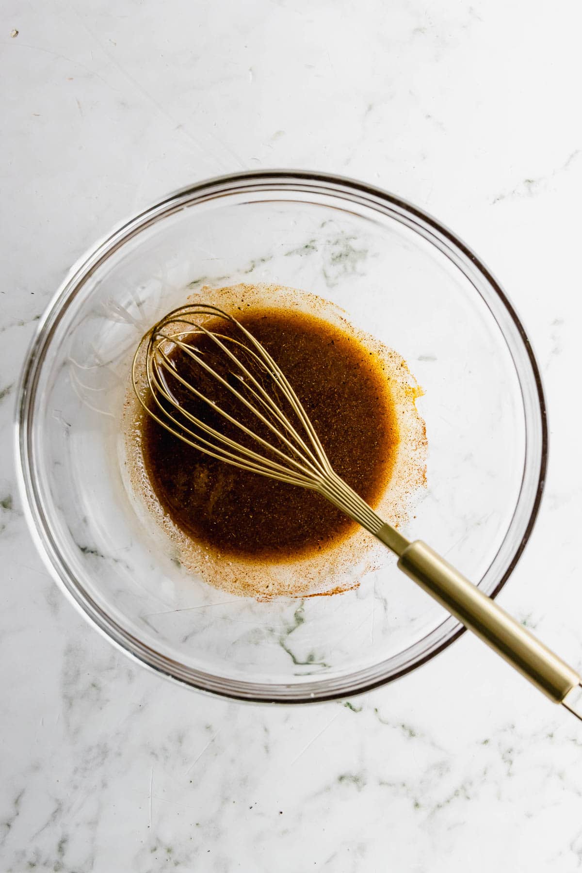 A bowl with a whisk and sauce in it.