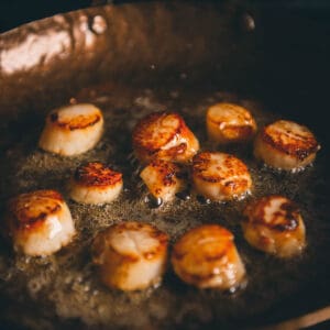 Scallops in a frying pan on a stove.