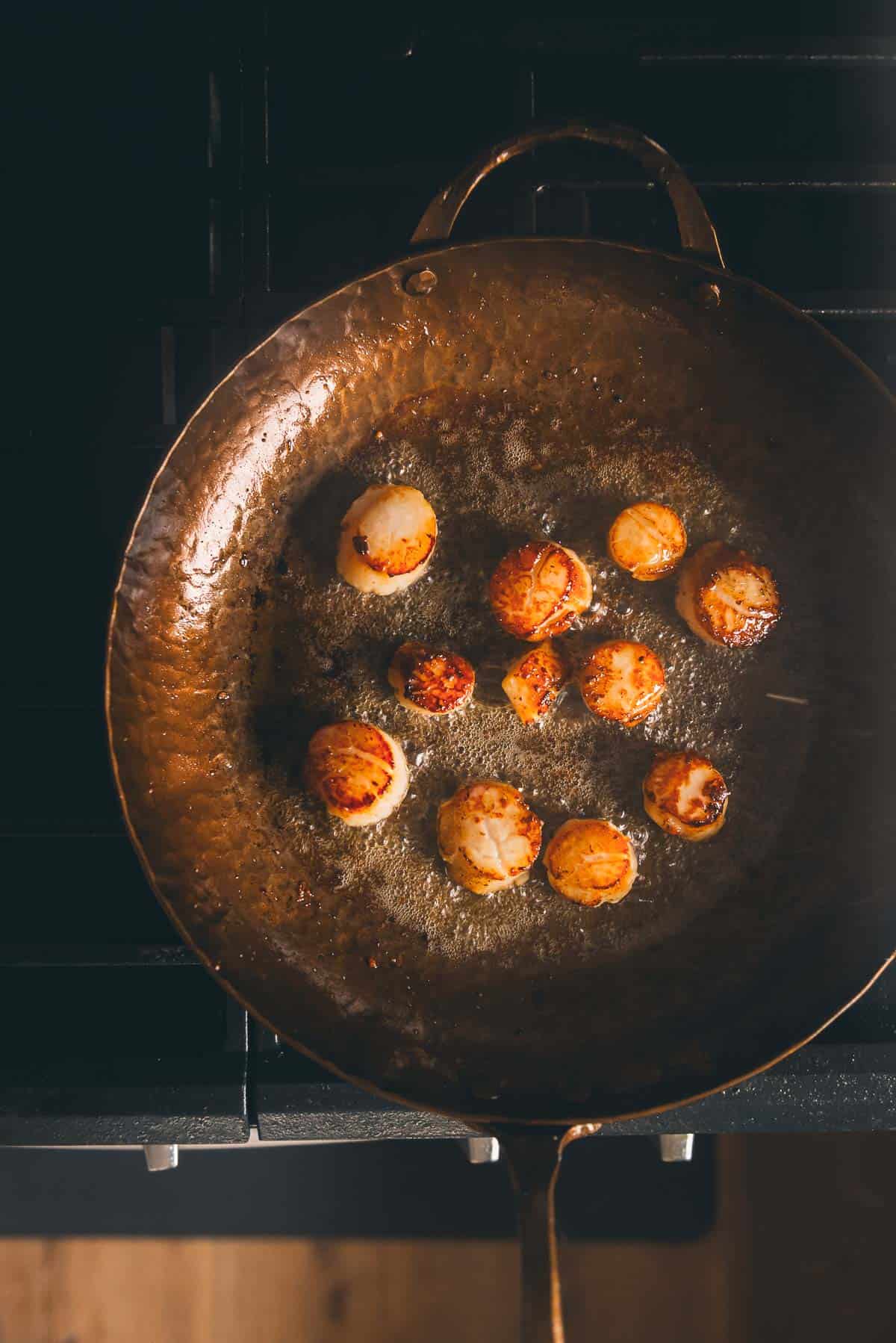 Scallops in a frying pan on the stove.