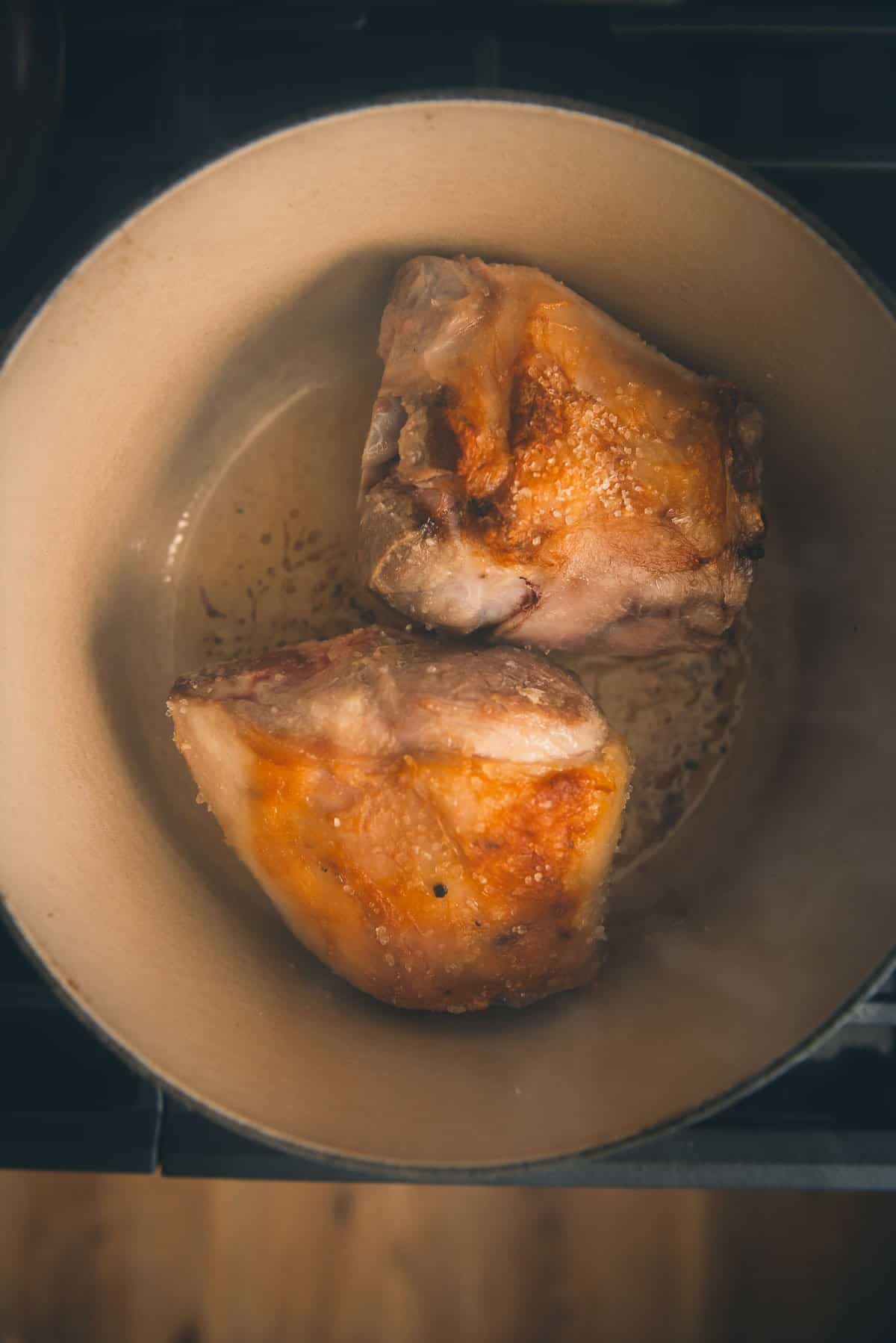 Pork shanks being browned in a dutch oven.