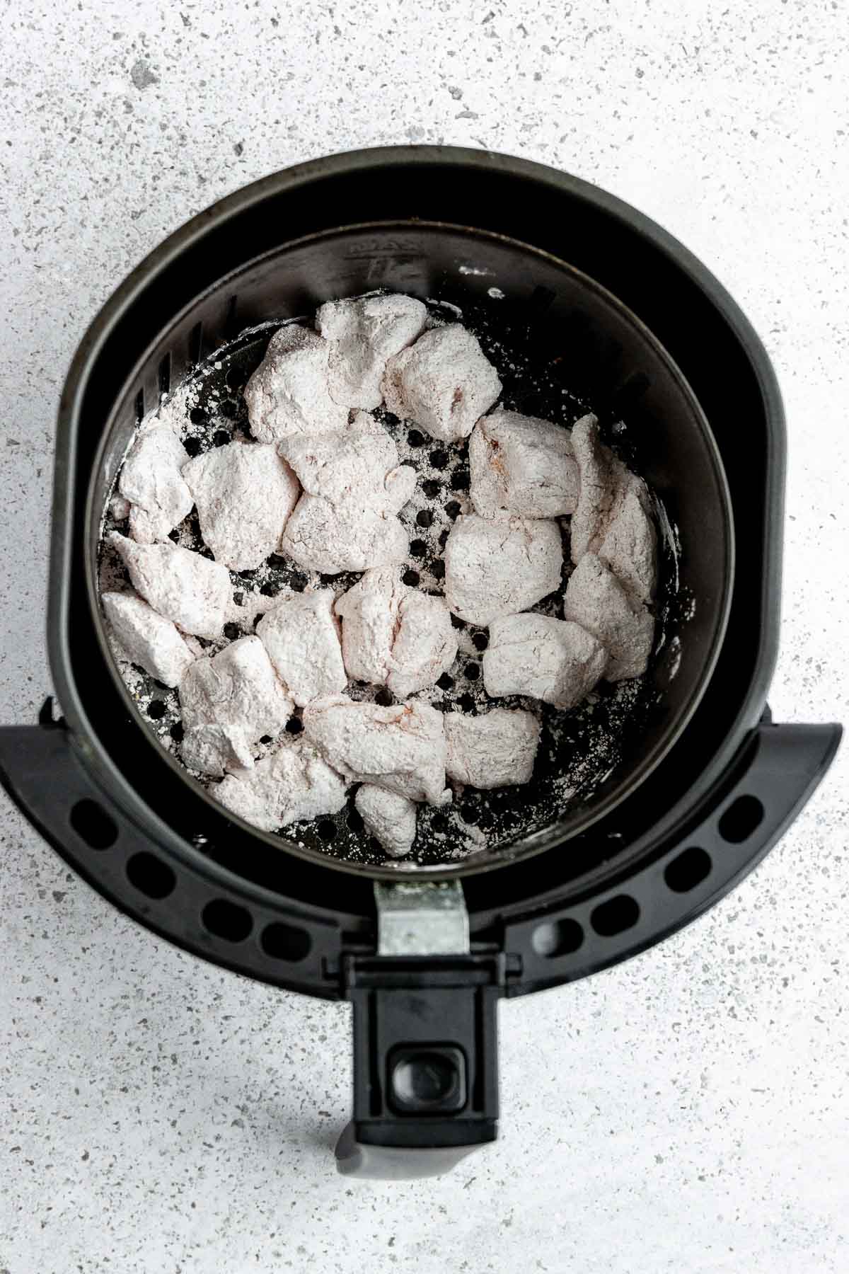 Coated chicken pieces in an air fryer.