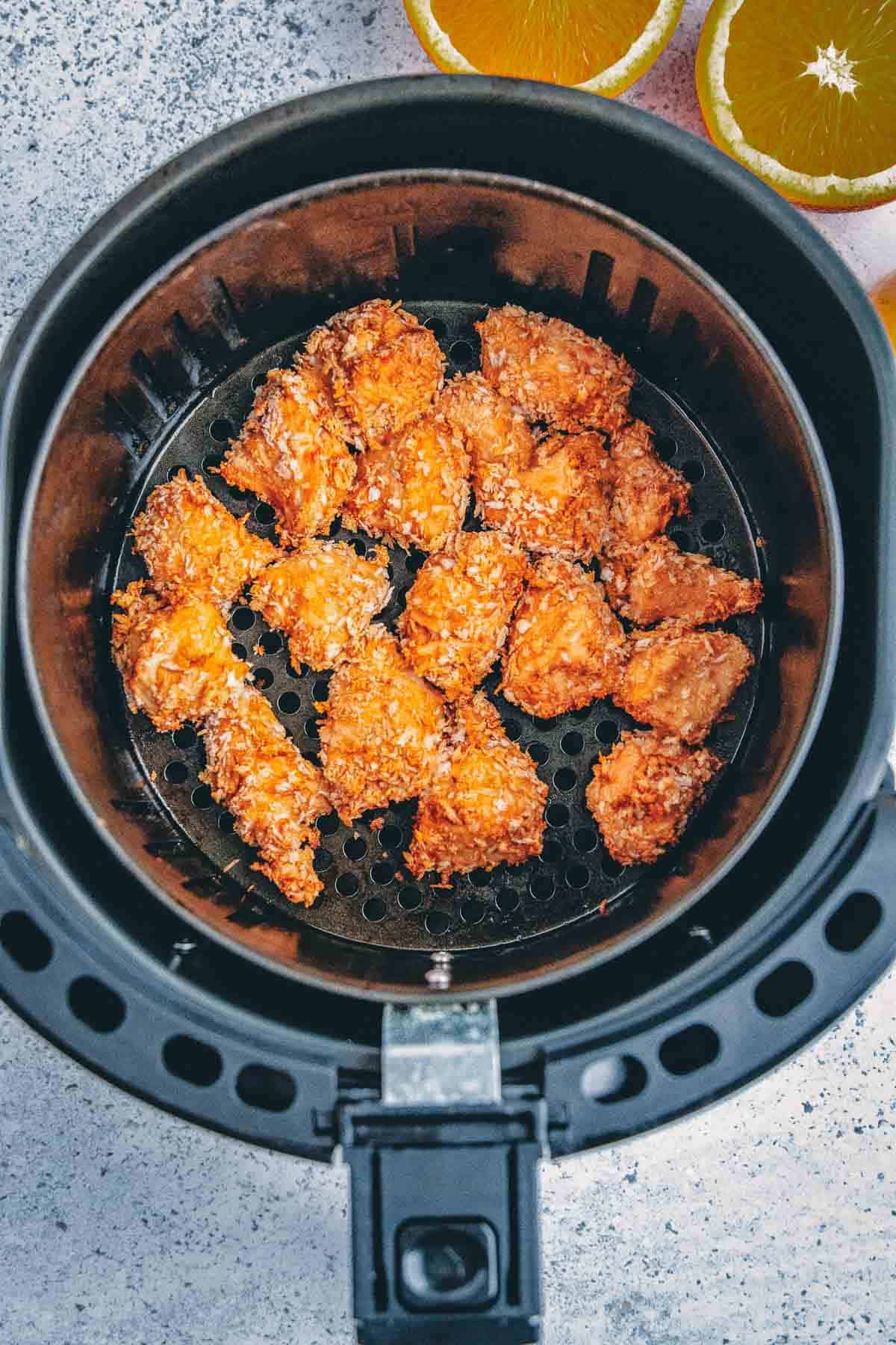 Orange chicken in the air fryer basket cooked to golden brown.