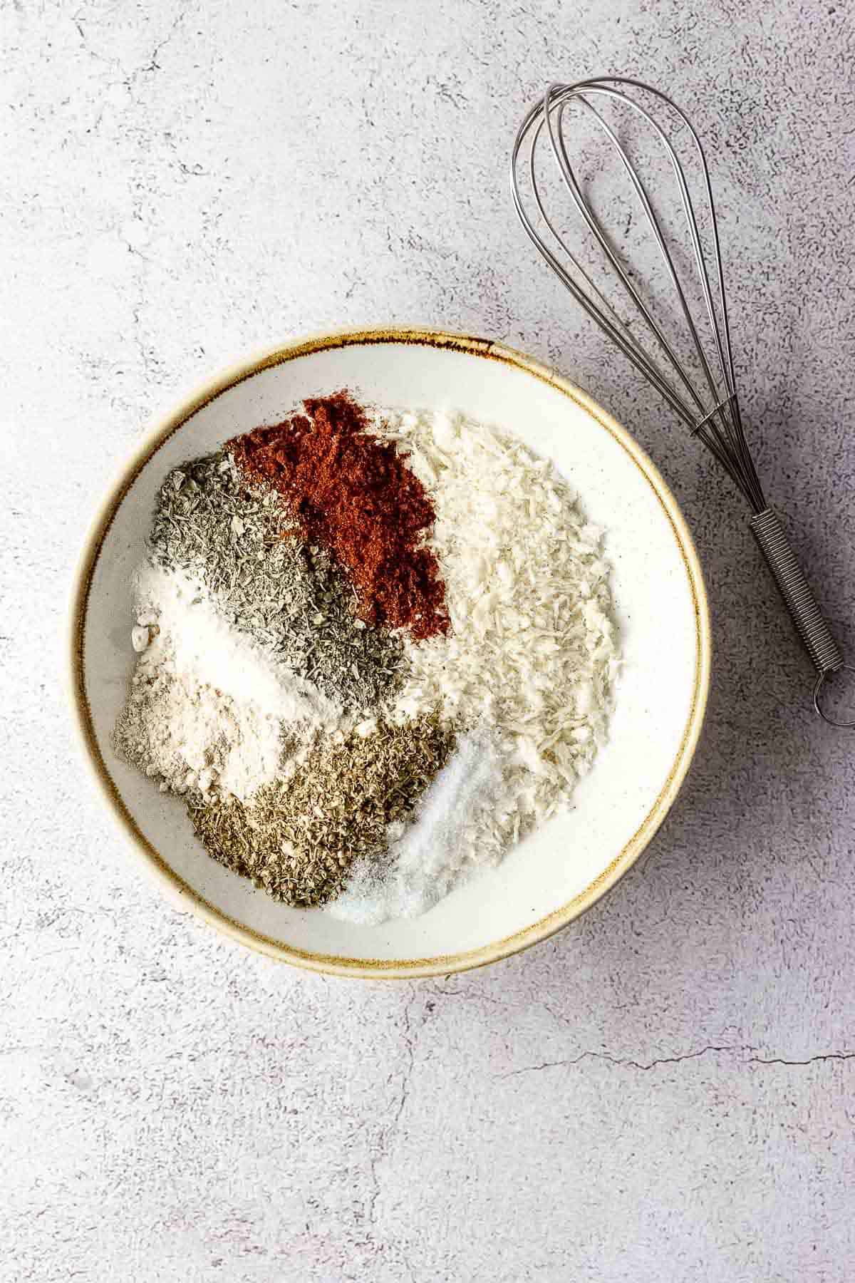 A bowl with spices, panko, and a whisk.