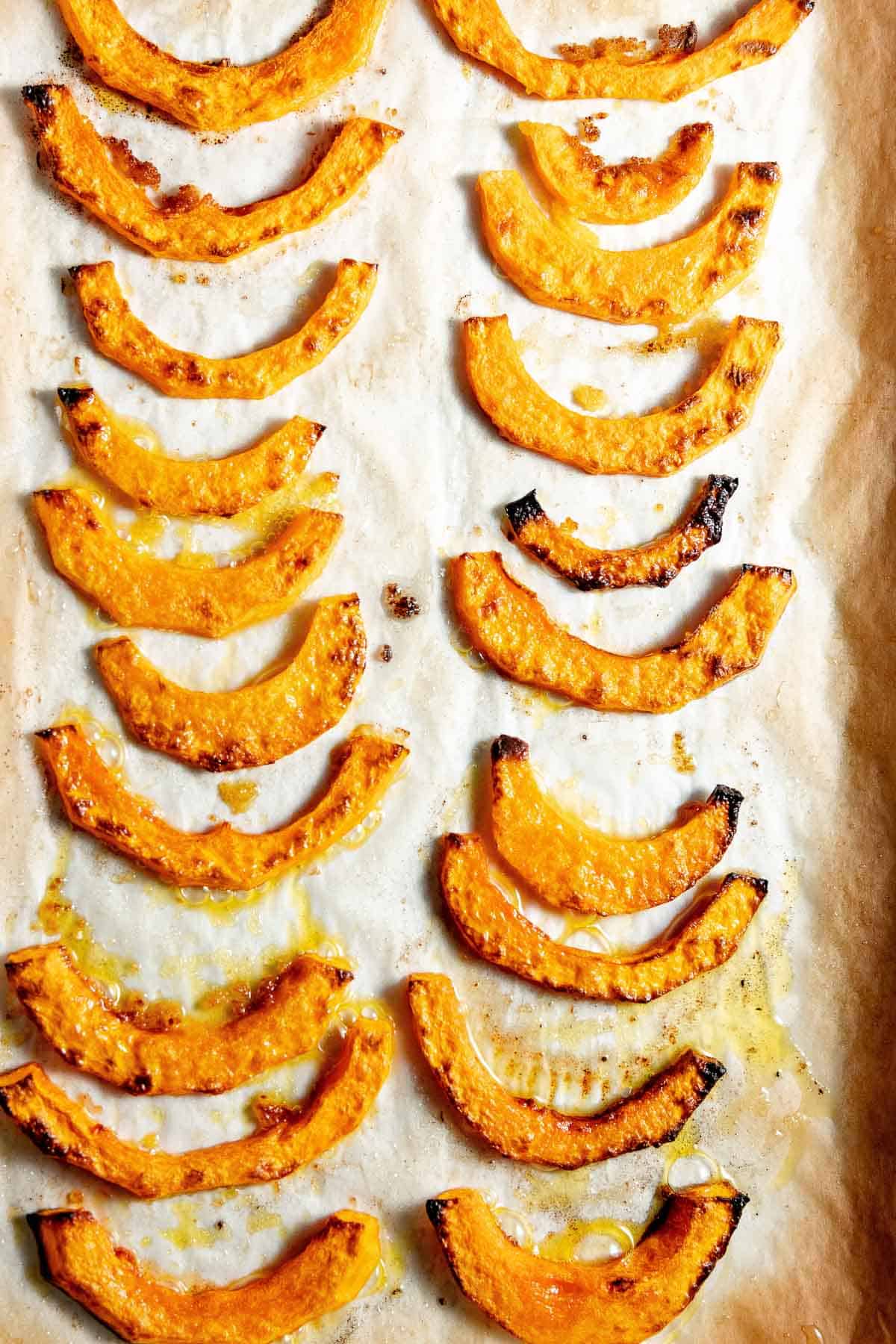 Roasted butternut squash slices on a baking sheet.