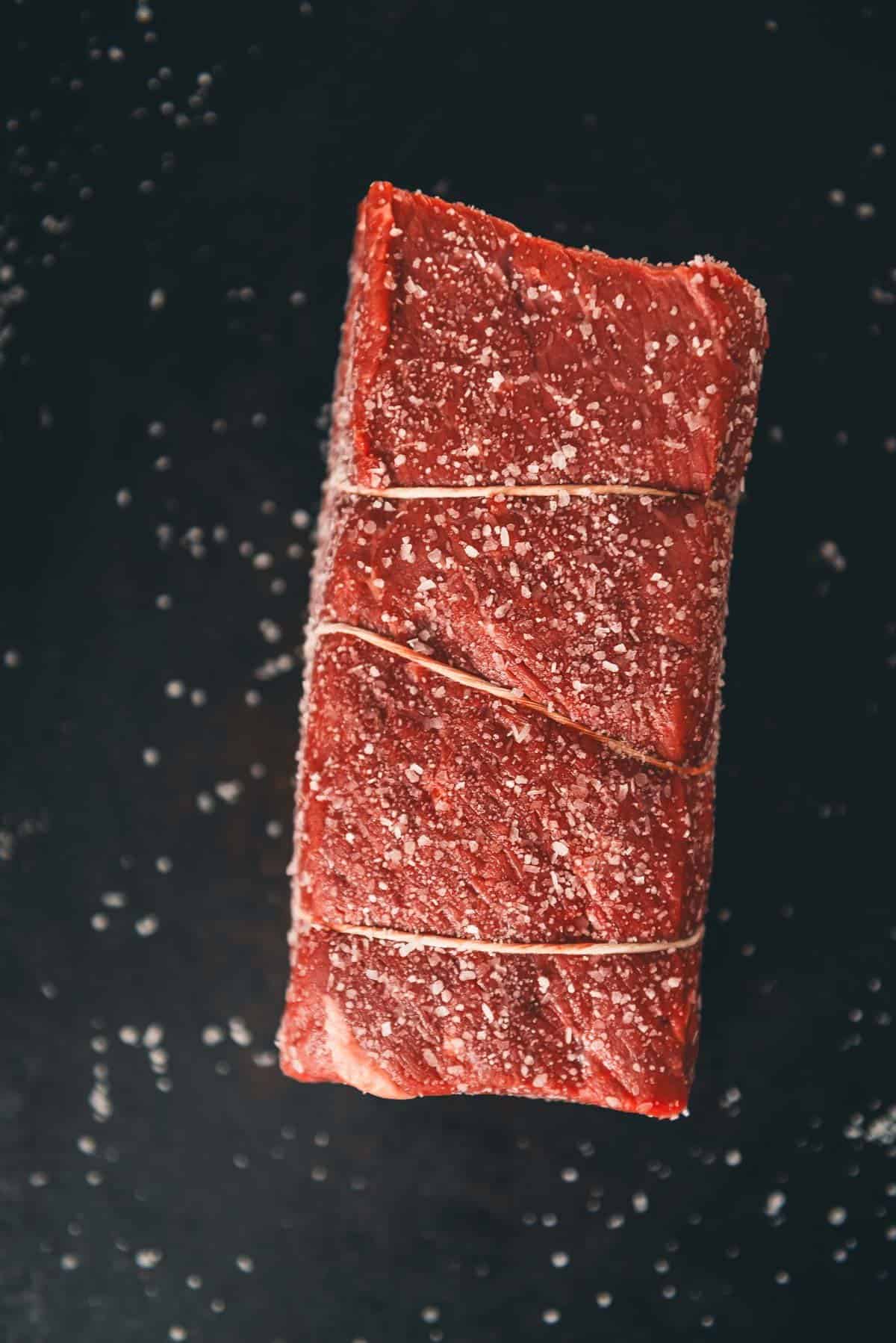 A piece of red meat on a black background.