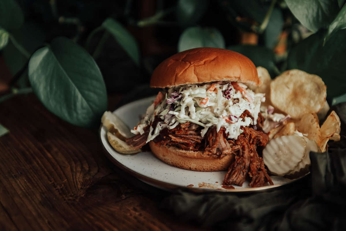 Slow Cooker pulled pork on a bun with slaw and pickles.