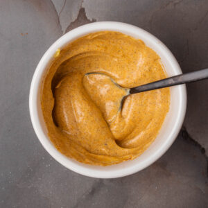 A bowl of Turmeric aioli with a spoon in it.