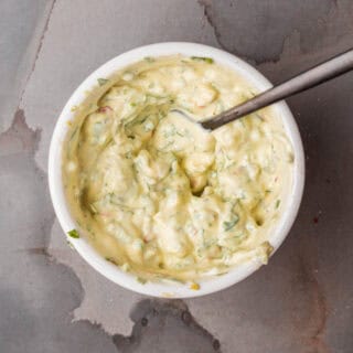 A bowl of cilantro avocado aioli with a spoon in it.