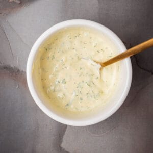 A bowl of herb aioli with a spoon.