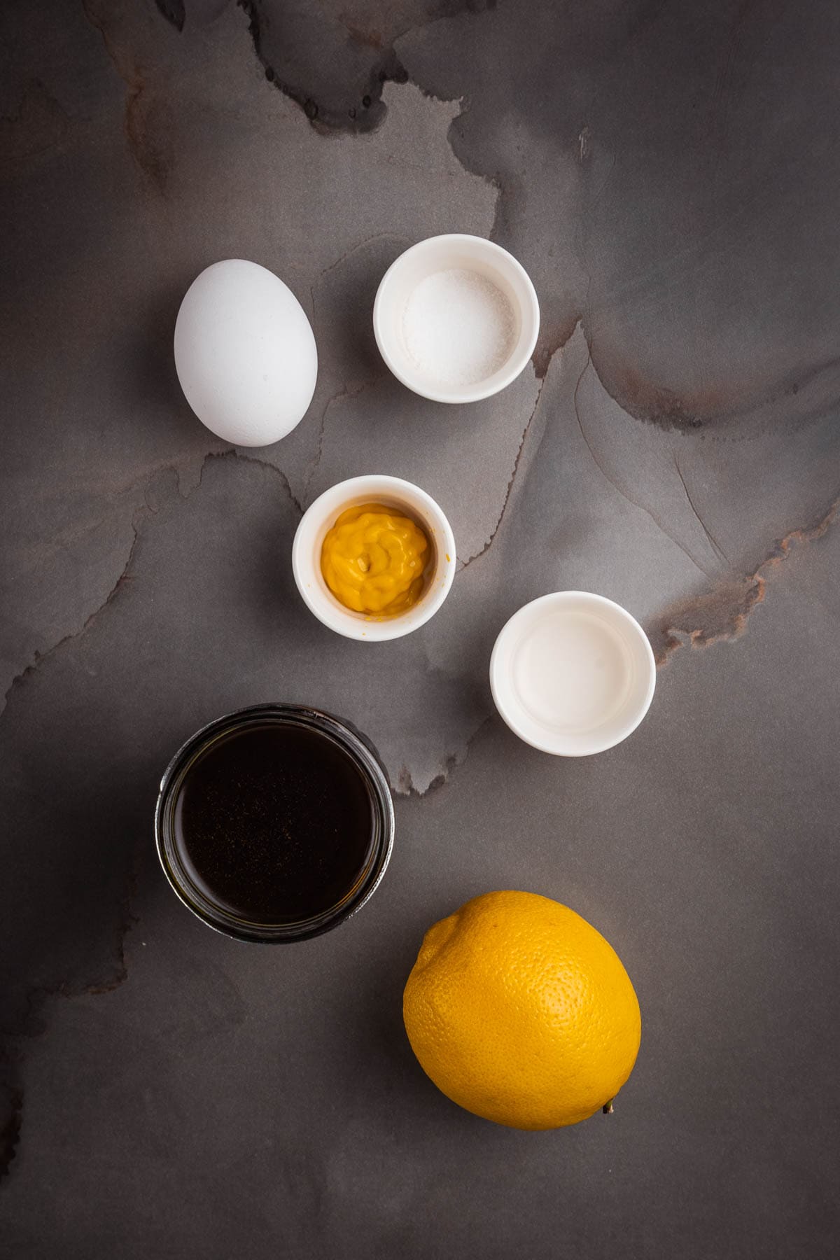 A bowl of lemon juice, eggs, and other ingredients on a gray background.