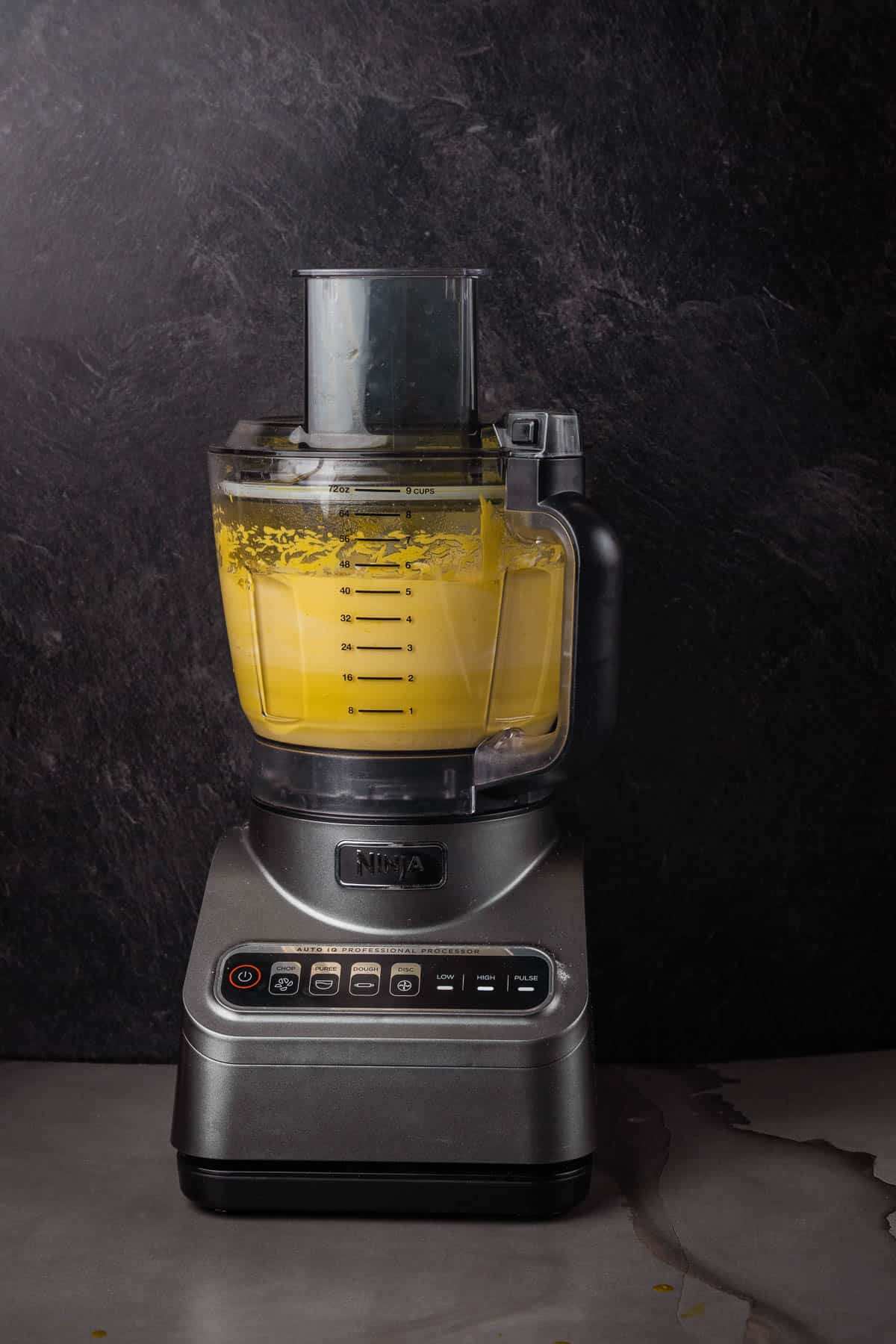 A food processor with yellow liquid in it.